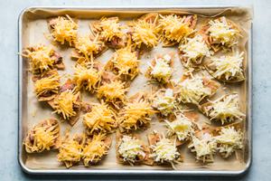 tortilla chips on a baking sheet topped with refried beans, cheese, steak, chicken