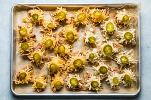 tortilla chips on a baking sheet topped with refried beans, cheese, steak, chicken and jalapeños