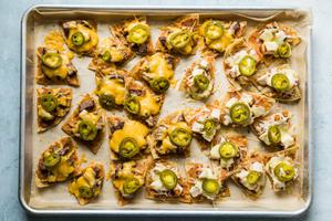 tortilla chips Baked on a baking sheet topped with refried beans, cheese, steak, chicken and jalapeños