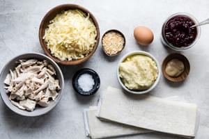 puff pastry, Dijon mustard, Egg, Gruyère, Onion, Flaky salt, shredded turkey and cranberry sauce in bowls on the counter