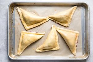 unbaked puff pastry turkey hand pies on a baking sheet