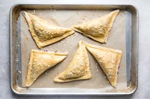 Unbaked Turkey Hand Pies sprinkled with minced onion and flaky salt on a baking sheet