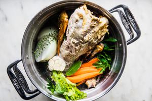 ingredients for turkey stock in a pot: onion, garlic, celery, carrots, thyme, parsley, salt, bay leaves & peppercorns
