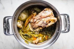 homemade turkey stock in a pot made with onion, garlic, celery, carrots, thyme, parsley, salt, bay leaves & peppercorns