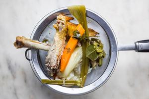 homemade turkey stock being poured through a fine mesh sieve