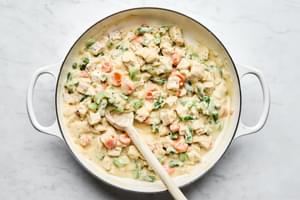 turkey and green beans being added to a skillet of turkey shepherds pie filling
