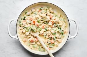 turkey and green beans being added to a skillet of turkey shepherds pie filling