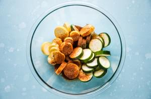 sliced zucchini and yellow squash sprinkled with taco seasoning in a glass bowl on the counter