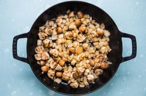zucchini, yellow squash, mushrooms and onions being cooked in olive oil in a skillet