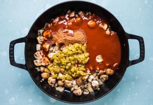 cooked vegetables in a skillet with taco seasoning, green chilies and enchilada sauce for vegetarian enchilada skillet