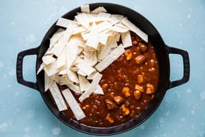 cooked vegetables, taco seasoning, green chilies, enchilada sauce and cut up corn tortillas in a skillet