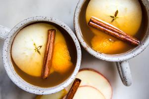 homemade wassail in mugs garnished with apple slices and cinnamon sticks