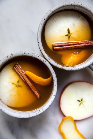 homemade wassail in mugs garnished with apple slices and cinnamon sticks