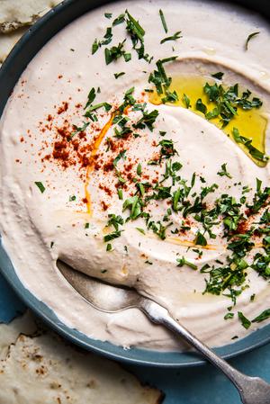 homemade White Bean Hummus in a bowl with paprika, olive oil and parsley