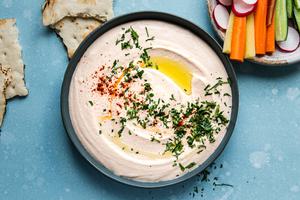 homemade White Bean Hummus in a bowl with paprika, olive oil and parsley served with veggies