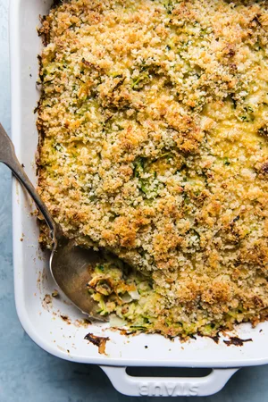 zucchini bake made with onions, dijon, garlic, parmesan, eggs, gruyere cheese, panko bread crumbs and butter