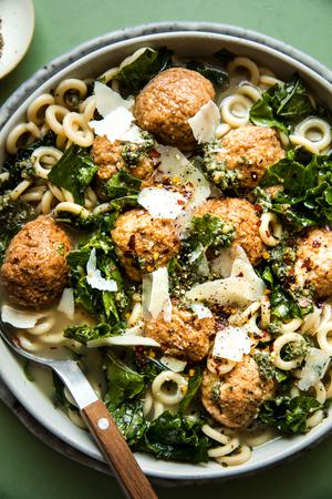 5-ingredient chicken meatball soup with kale and parmesan in a bowl with a spoon