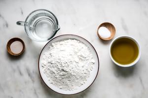 bowl of all purpose flour, olive oil, salt, water and yeast on the counter
