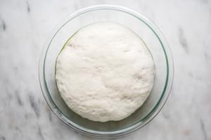 homemade focaccia bread dough rising in a bowl with olive oil
