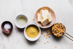 popcorn kernels, butter, vegetable oil, salt, and nutritional yeast in bowls on a counter