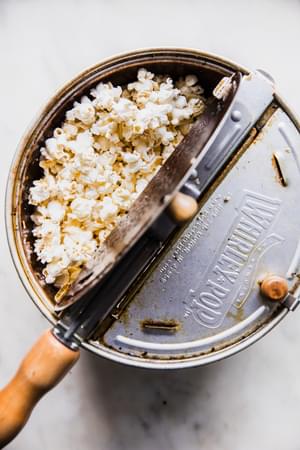 a whirly pop full of homemade popcorn being popped in vegetable oil