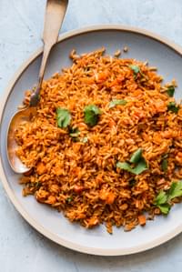 large plate of restaurant style Mexican rice on a large plate with a large spoon.