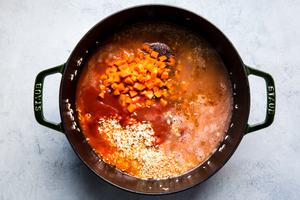 toasted rice with stock, carrots and tomatoes shown in a large pot