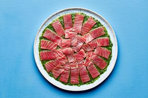 homemade sauce for aguachile spread evenly on a serving platter topped with thinly sliced, raw sushi-grade ahi tuna