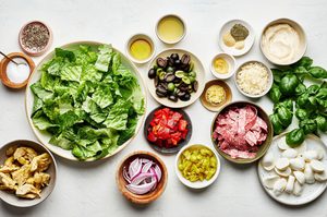 ingredients in bowls on the counter to make antipasto salad and creamy parmesan lemon dressing