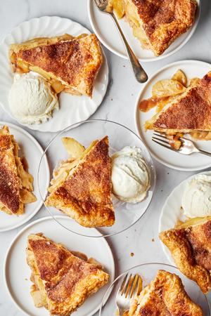 several slices of homemade apple pie on plates served with vanilla ice cream