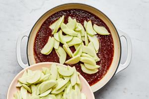 apples that have been sliced, cored, and peeled being poured into a pot with apple pie filling