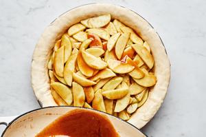 homemade apple pie filling made with butter, brown sugar, sugar and spices being poured into a homemade pie crust
