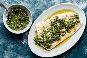homemade Baked Cod with Parsley Olive Tapenade on a serving plate with a serving fork next to a bowl of extra tapenade