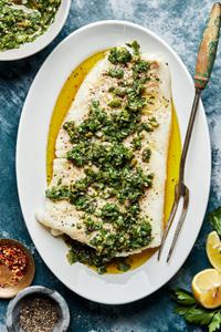 homemade Baked Cod with Parsley Olive Tapenade  on a serving plate with a serving fork next to a bowl of extra tapenade