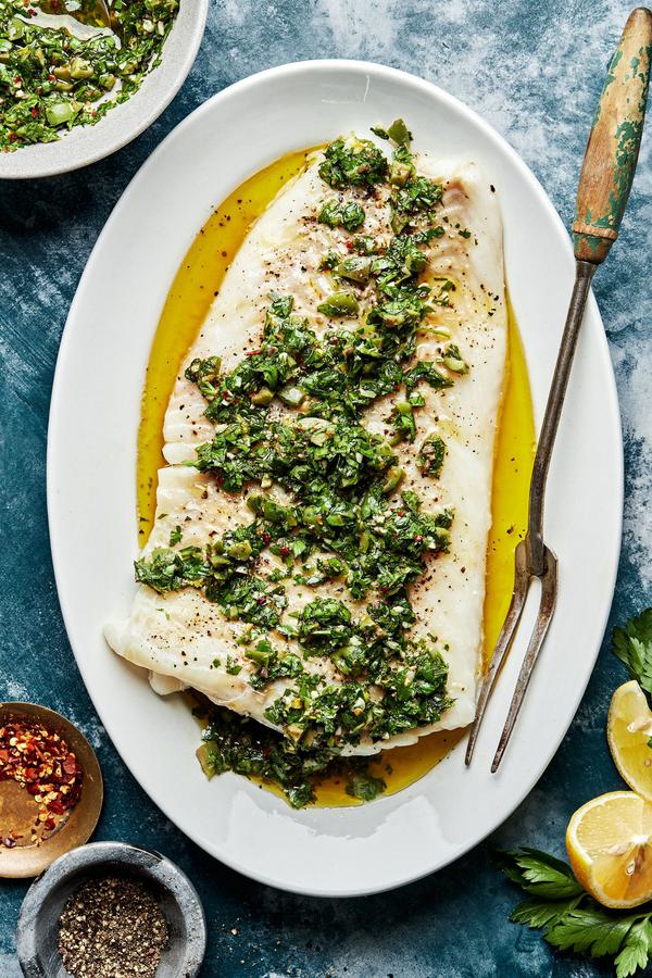 homemade Baked Cod with Parsley Olive Tapenade on a serving plate with a serving fork next to a bowl of extra tapenade