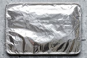 pork ribs covered in homemade dry rub on a baking sheet covered with foil ready to be baked in the oven
