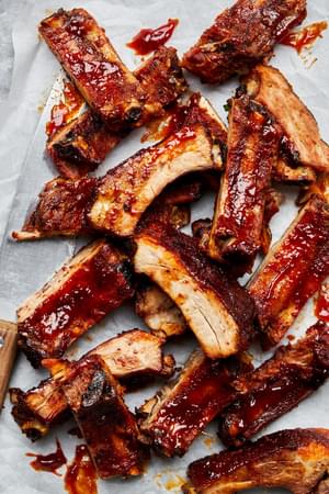 baked pork ribs slathered with homemade bbq sauce on top of parchment paper