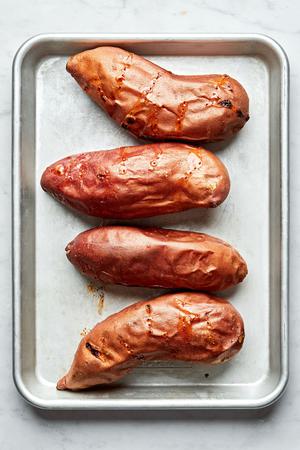 4 baked sweet potatoes on a sheet pan