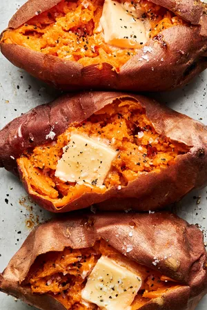 homemade baked sweet potatoes cut open topped with butter, salt & pepper