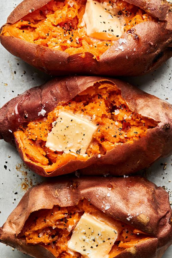 homemade baked sweet potatoes cut open topped with butter, salt & pepper