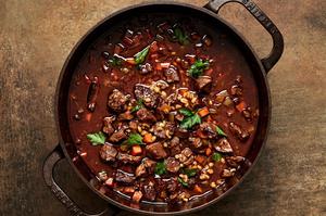 a pot of homemade beef & barley soup made with tomato paste, bouillon & stock, soy sauce, vegetables and spices