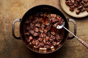 chuck roast seasoned with salt being browned in a pot with olive oil