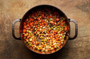 onion, carrots and celery being cooked in a pot with olive oil for beef & barley soup
