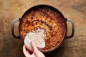barley being added into a pot of homemade beef & barley soup