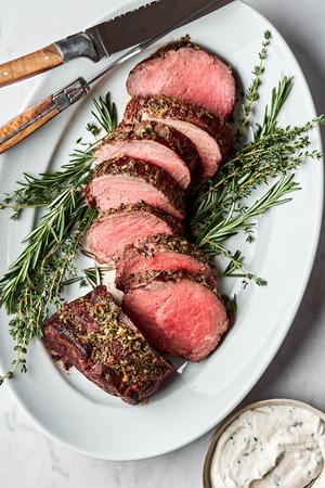 homemade beef tenderloin cooked with garlic herb butter sliced on a serving platter served with horseradish sauce
