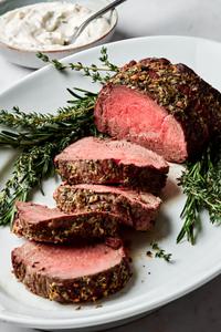 homemade beef tenderloin cooked with garlic herb butter sliced on a serving platter served with horseradish sauce