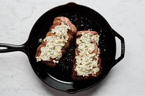 beef tenderloin seasoned with salt & pepper, seared in a skillet and covered with garlic herb butter ready for the oven