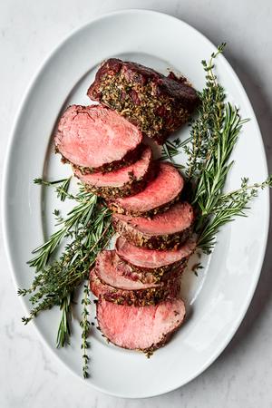 homemade beef tenderloin cooked with garlic herb butter sliced on a serving platter