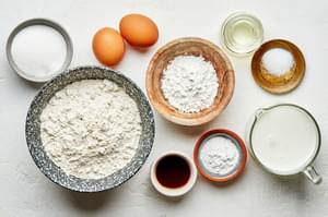 flour, sugar, cornstarch, baking powder, salt, eggs, milk, vegetable oil and vanilla in bowls for making Belgian waffles