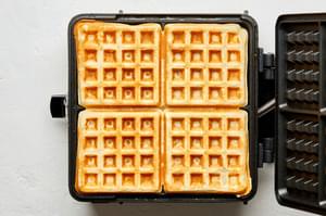 an open waffle iron with a cooked waffle inside